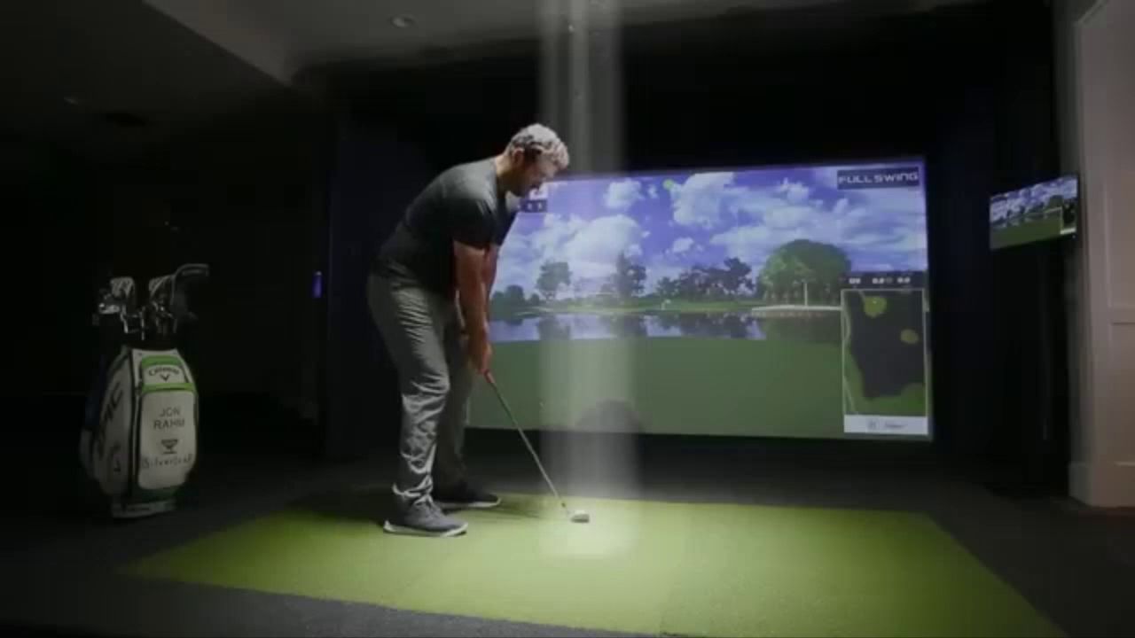 A golfer addressing the ball in a simulator bay